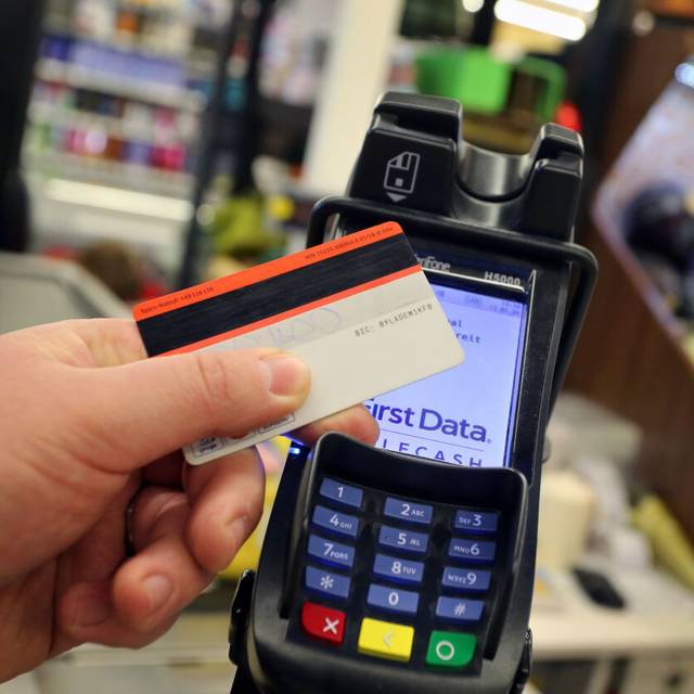 Eine Karte wird an den Bezahl-Terminal an der Kasse eines Supermarktes gehalten