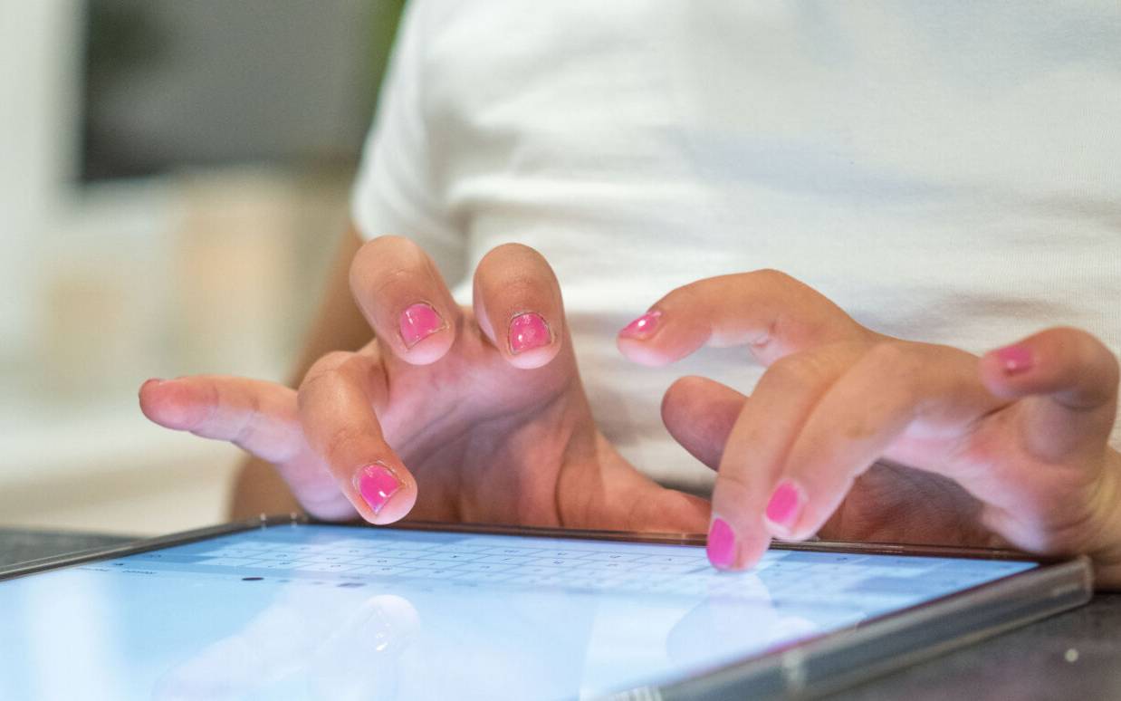 Eine Person tippt auf einem Tablet etwas ein.