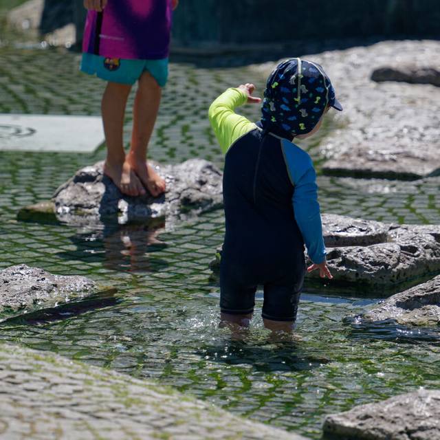 Kinder kühlen sich in einem Brunnen nahe des Rheins ab.