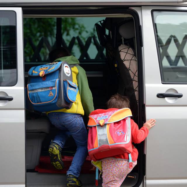 Vor einer Schule steigen Kinder ein privates Fahrzeug