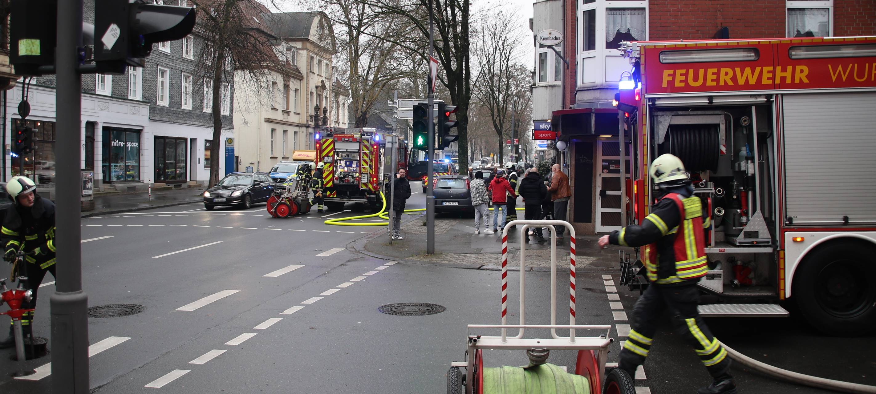Ein Feuerwehrwagen steht auf der Straße, ein Feuerwehrmann entrollt einen Schlauch