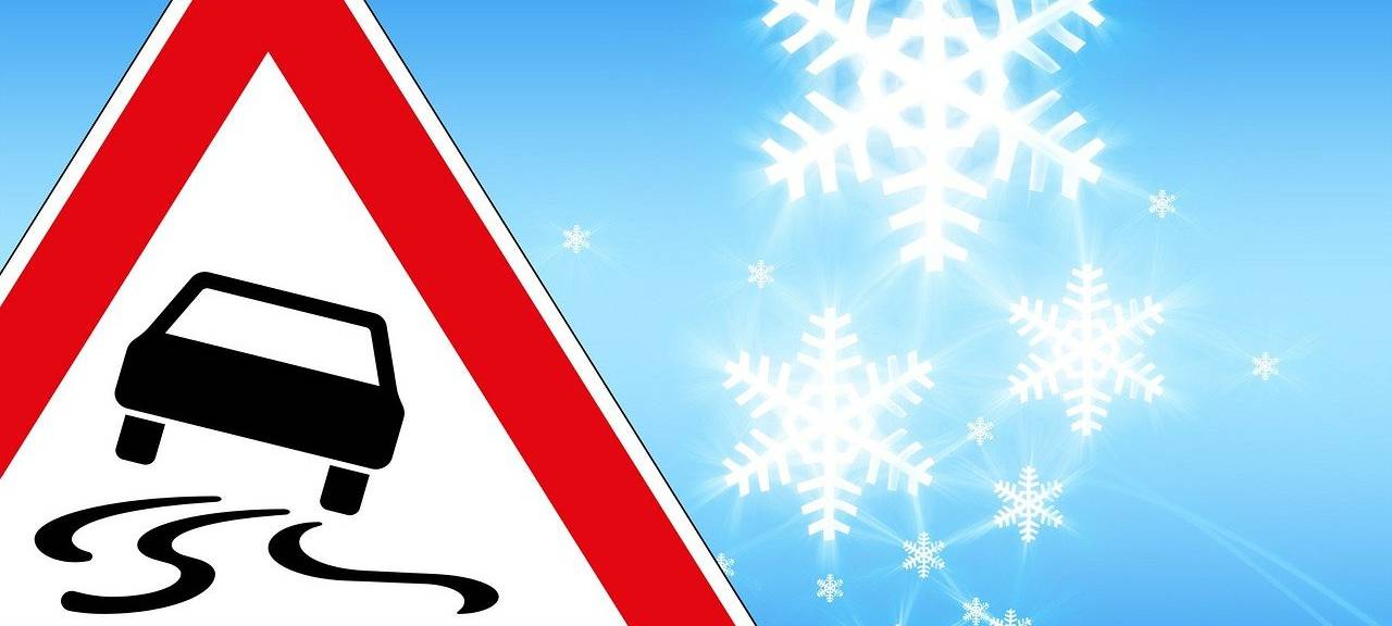 Ein Glatteis-Verkehrszeichen und Schneeflocken