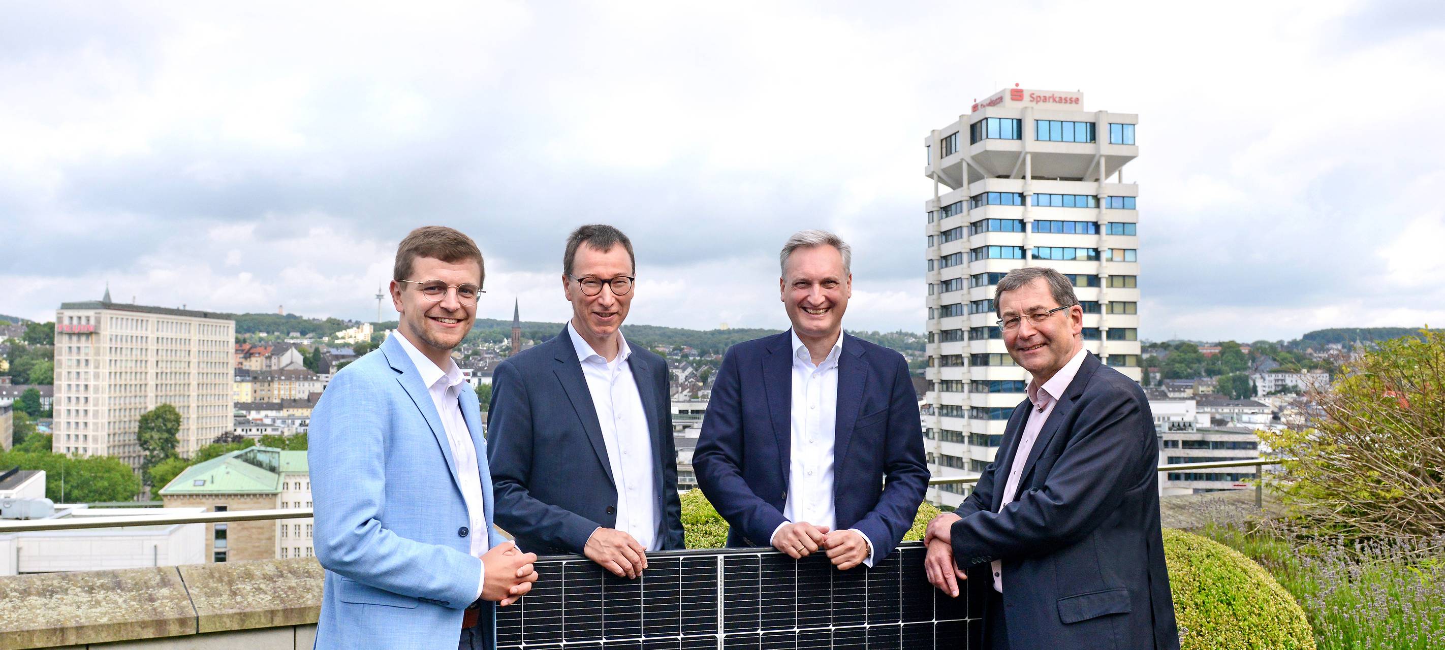 Die Chefs von WSW und Stadtsparkasse mit Solarzellen auf einem Dach