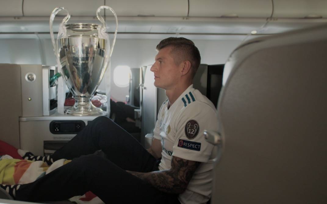Toni Kroos sitzt im Flugzeug mit dem Champions League Pokal